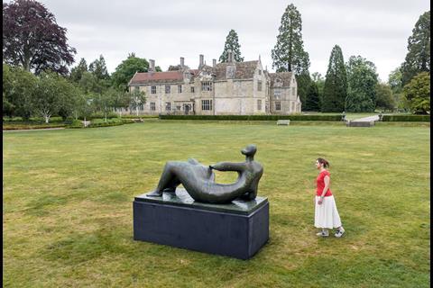 Woman looking at Henry Moore sculpture in front of mansion house